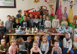 Grupa dzieci stoi przy stole pełnym pięknych ozdób świątecznych