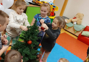 Dzieci ubierają choinkę.