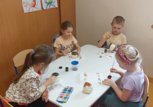Dzieci malują farbami pączki z papieru.