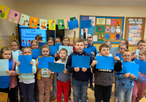 Uczniowie klas I-III trzymają niebieskie kartki w ramach solidarności z osobami ze spektrum autyzmu.