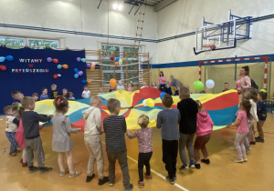 Dzieci podrzucają baloniki na chuście.