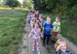 Dzieci spacerują leśnymi ścieżkami.