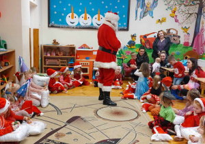 Dzieci siedzą w kółeczku na środku stoi Mikołaj