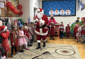 Mikołaj chodzi po sali, dzieci stoją w kółeczku