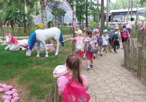 Dzieci wędrują ścieżką obok kolorowych jednorożców