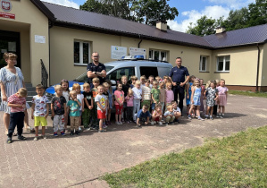 Dzieci wraz z policjantami stoją przed radiowozem