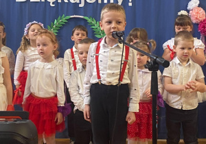 Chłopiec recytuje do mikrofonu wierszyk dla mamy i taty