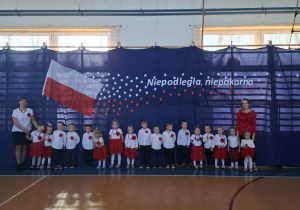 Grupa dzieci na tle dekoracji z okazji Dnia Niepodległości