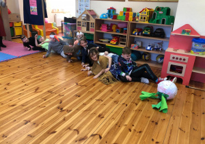 Na zdjęciu widać kilkoro dzieci leżących na podłodze. Wszyscy przewrócili się na siebie. Każde z nich jest uśmiechnięte.