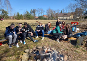 Uczniowie klasy 7 i 8 pieką kiełbaski w ognisku.