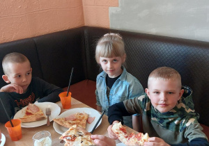 Dzieci częstują się pizzą.