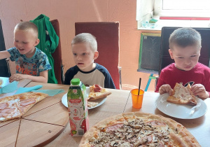 Dzieci jedzą pizzę i frytki.