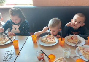 Dzieci częstują się pizzą i frytkami.