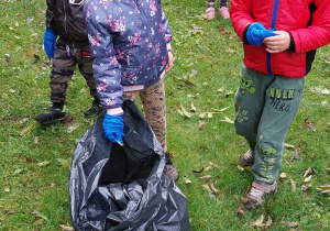 Dzieci wrzucają śmieci do wielkiego worka.