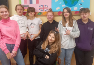 Uczniowie klasy ósmej stoją przed tablicą, na której wiszą plakaty dotyczące Europejskiego Dnia Języków