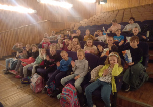 Zdjęcie przedstawia uczniów siedzących w sali widowiskowej MDK w Opocznie.