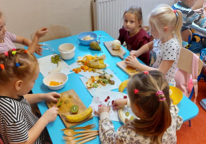Dzieci kroją owoce na sałatkę owocową.
